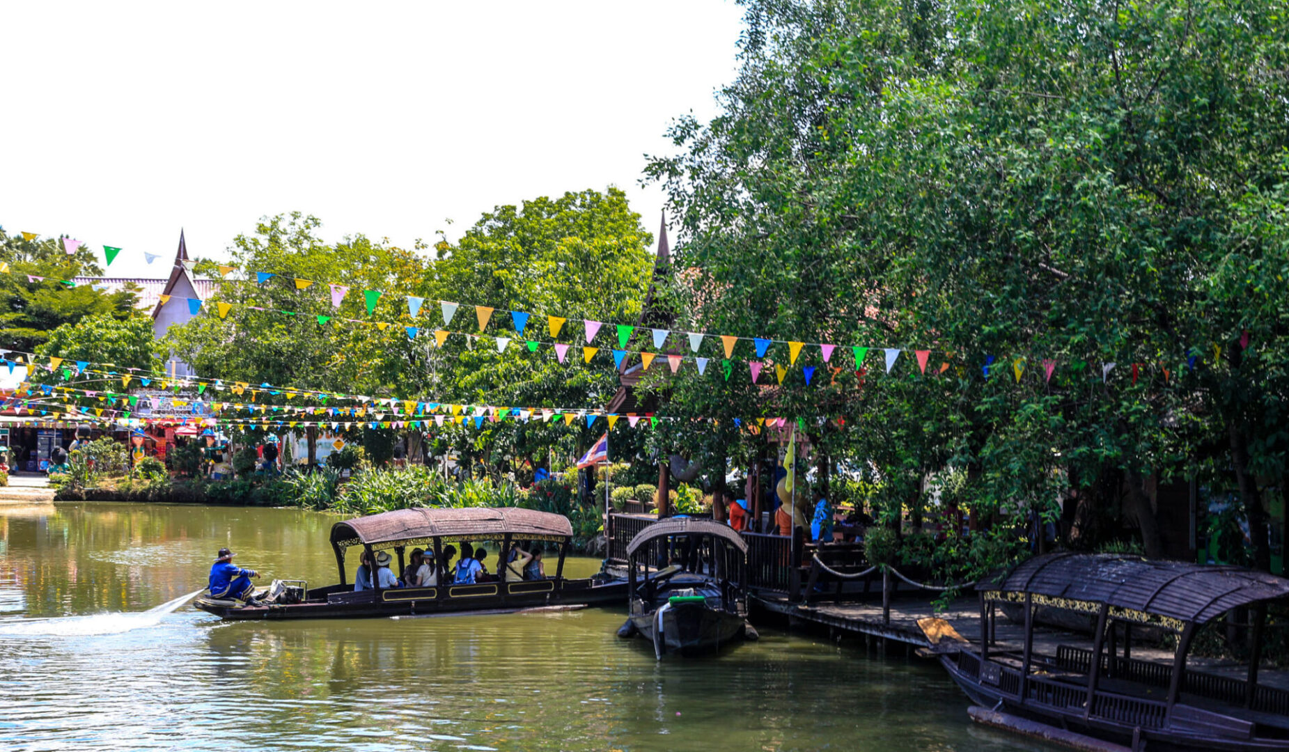 Boats on scenic river with colorful flags.
