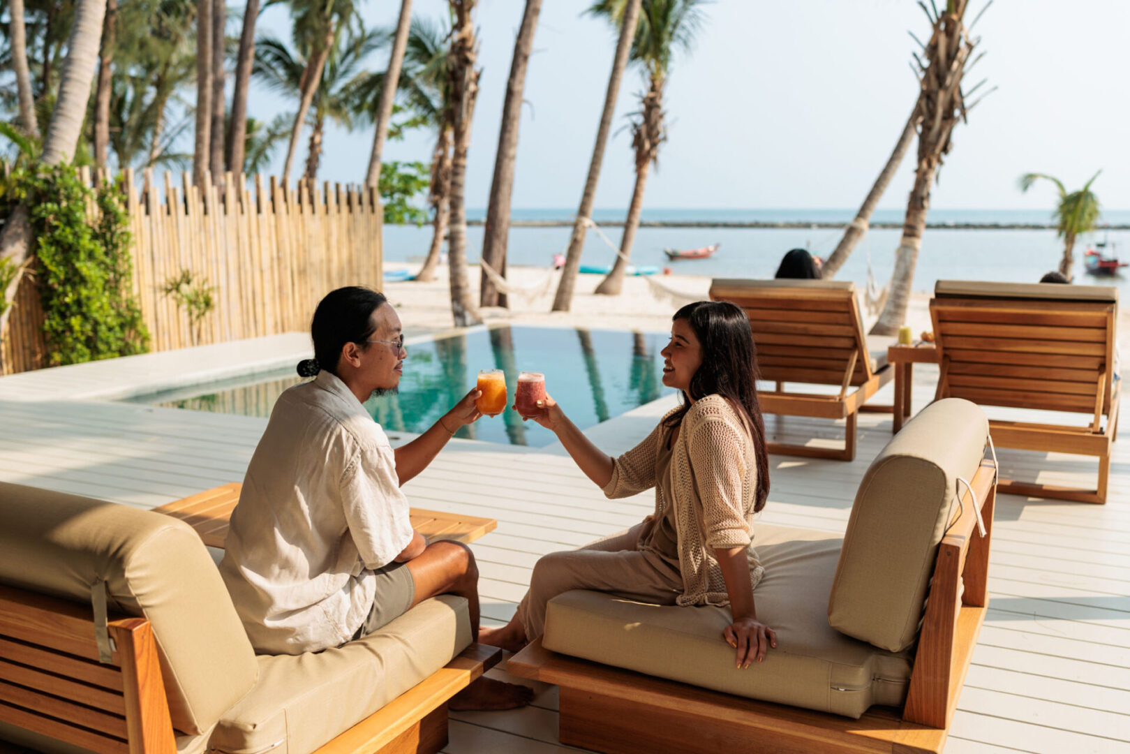 Two women toasting drinks by the pool.