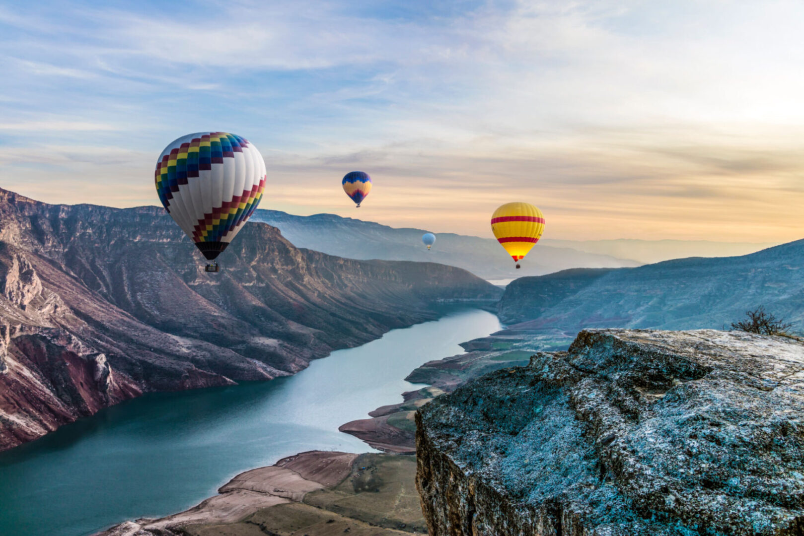 Hot air balloons over scenic canyon landscape.