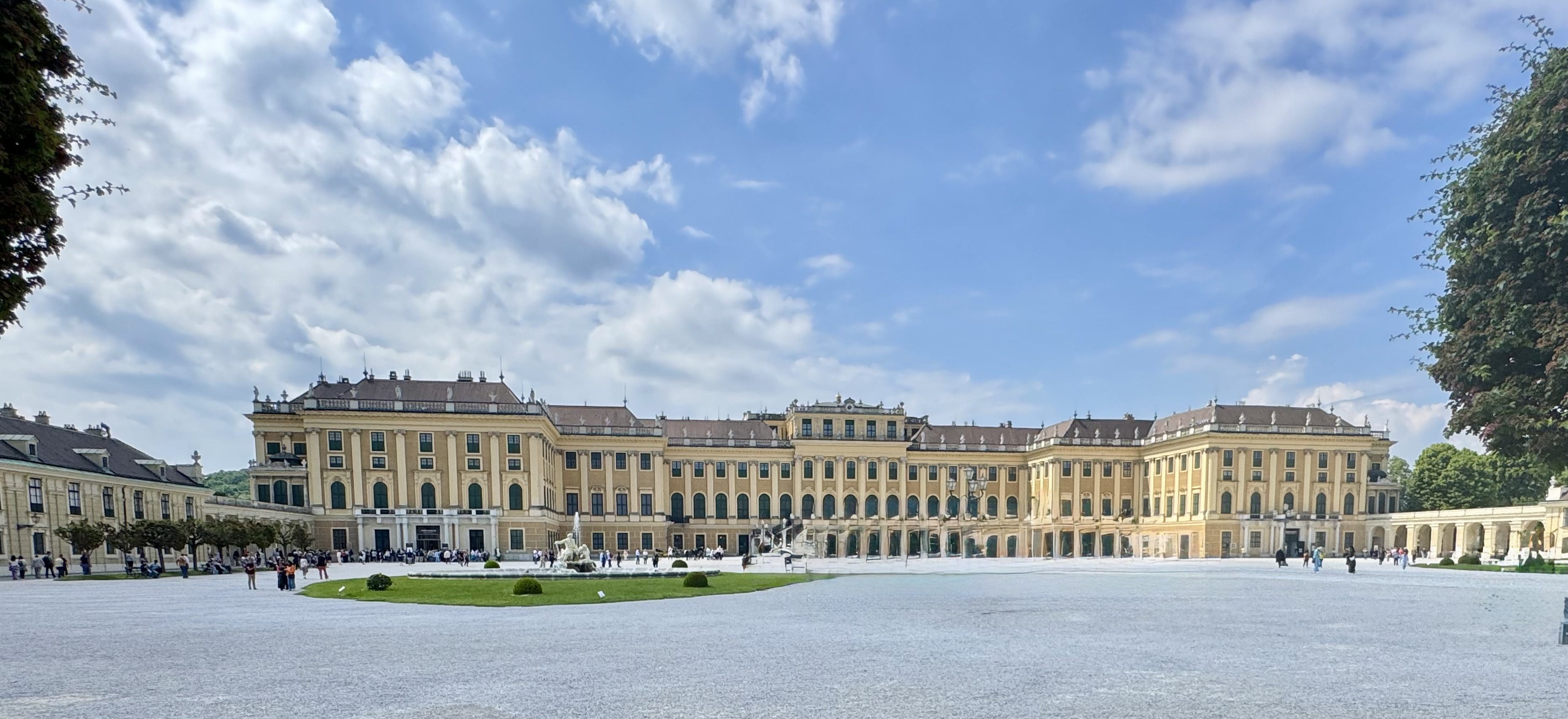 Grand historic palace with expansive courtyard under a blue sky.