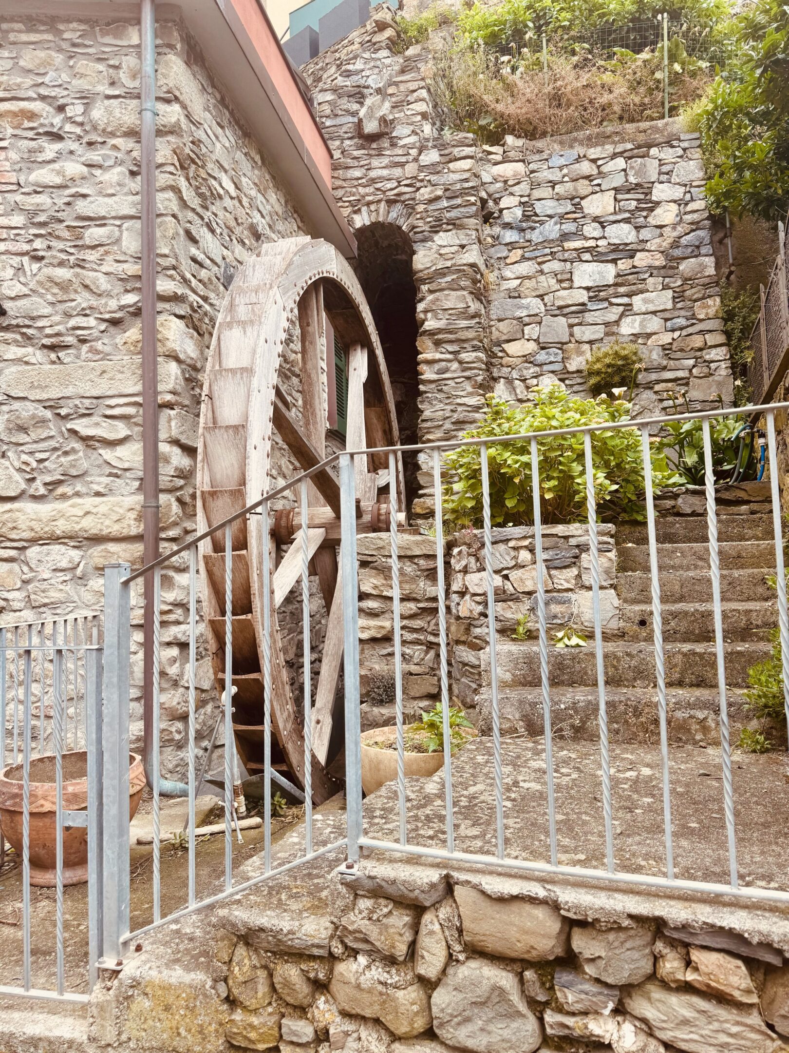 Old stone building with a large wooden water wheel beside it.