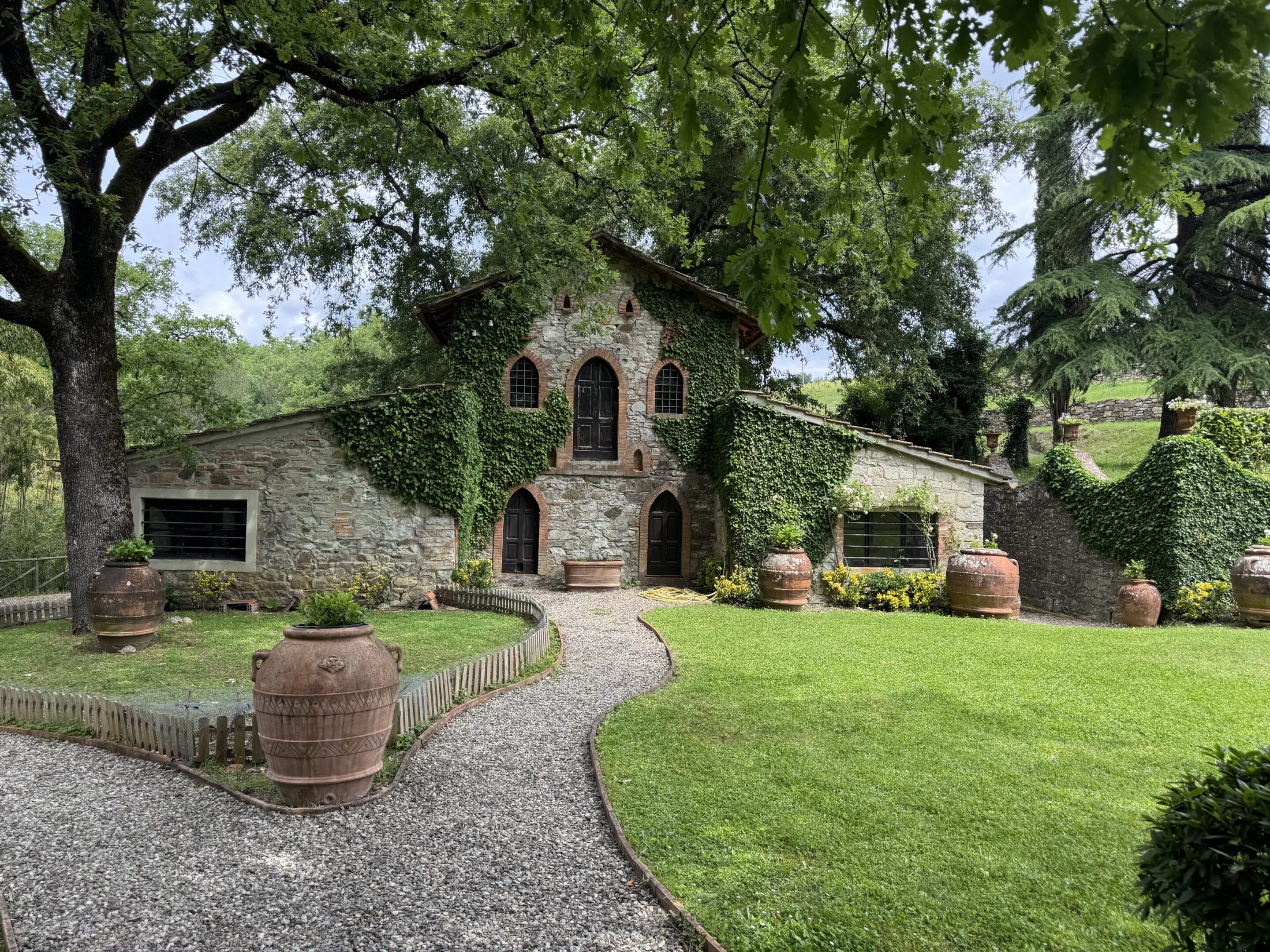 Charming stone house covered in ivy with a path and greenery.