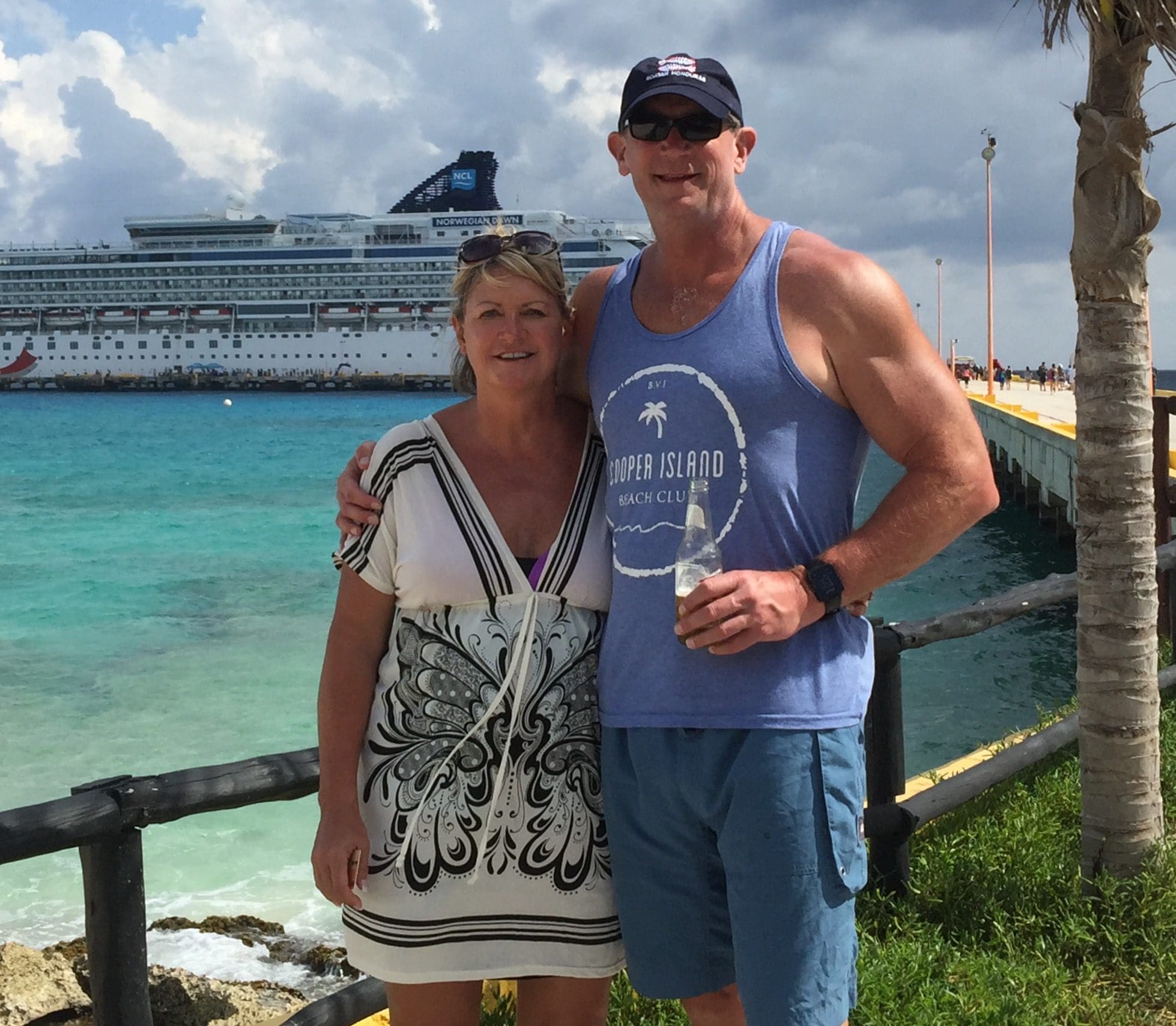 Couple posing by the waterfront with a cruise ship in the background.