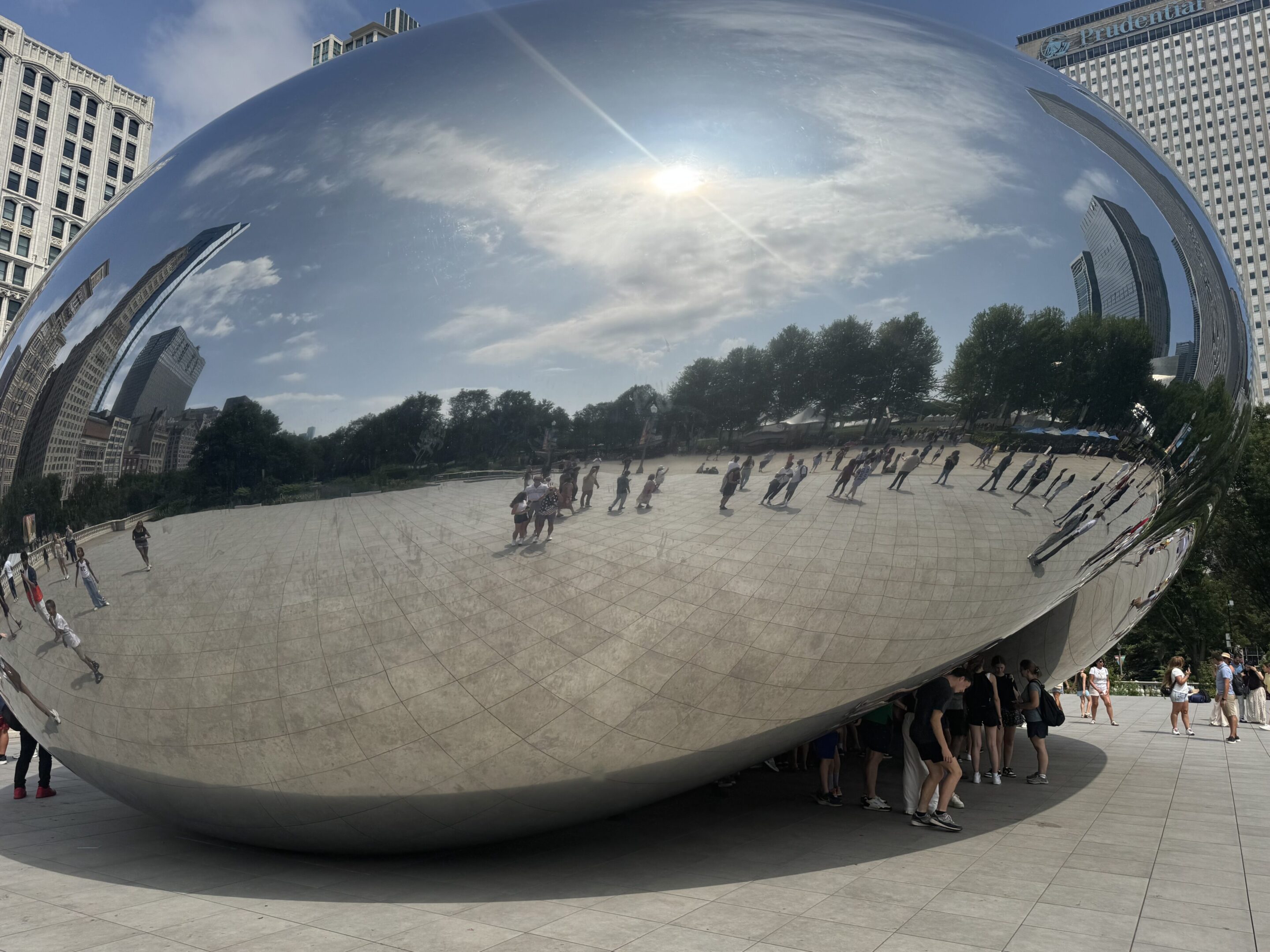 Reflection of people and sky on the shiny Cloud Gate sculpture in Chicago.