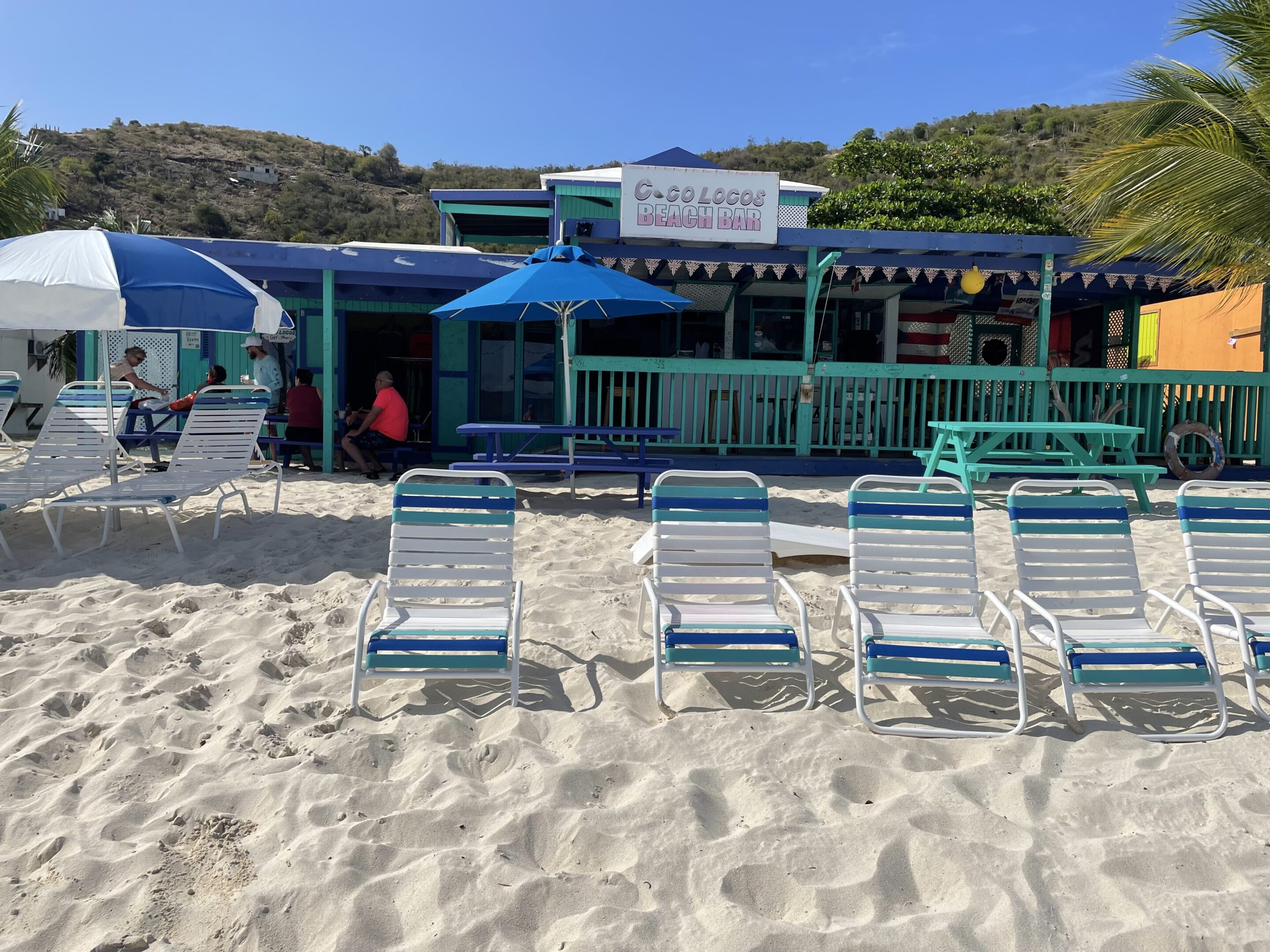 Beachfront café with seating and umbrellas on a sunny day.