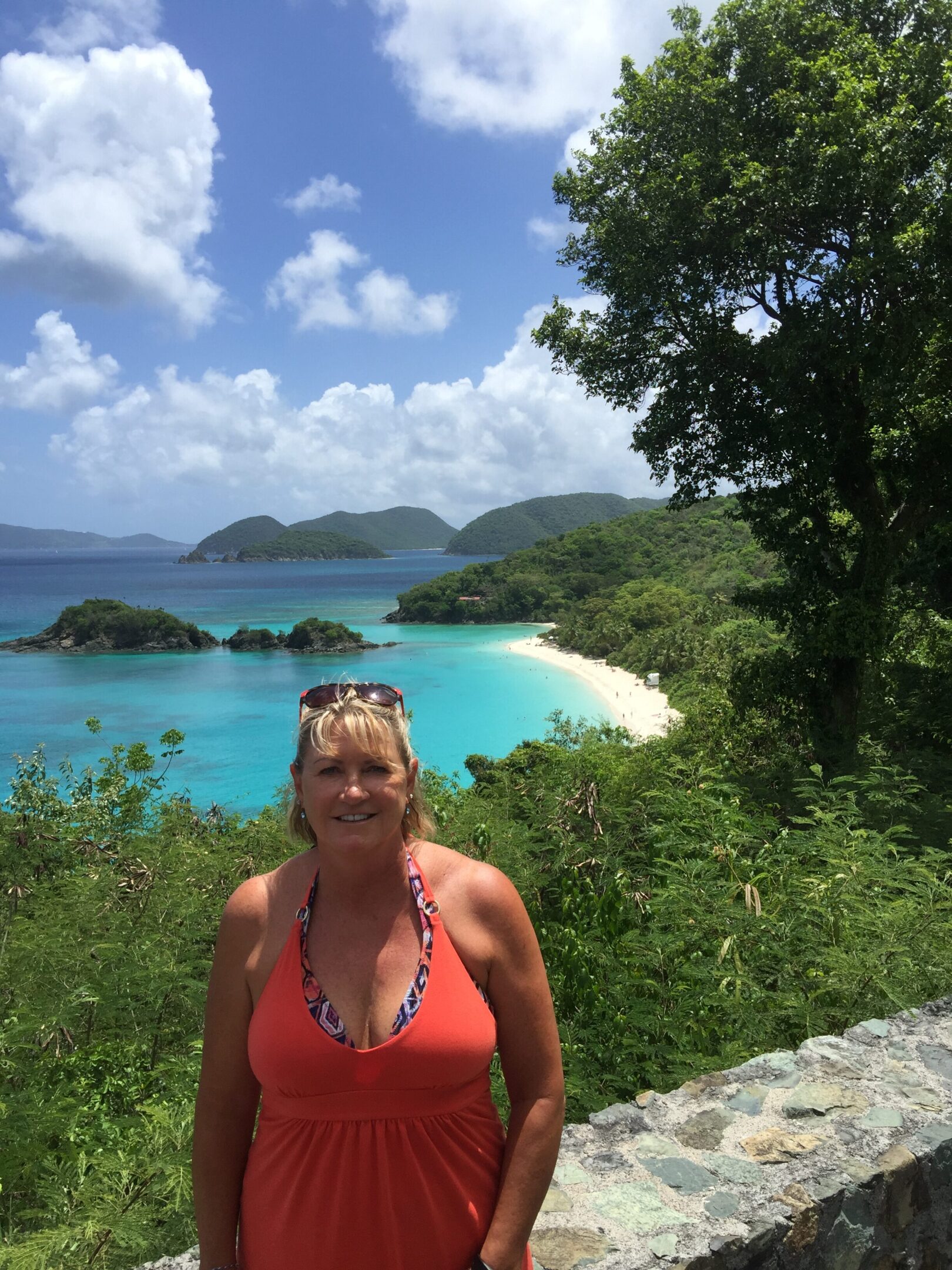 Woman smiling with tropical beach and islands in the background.